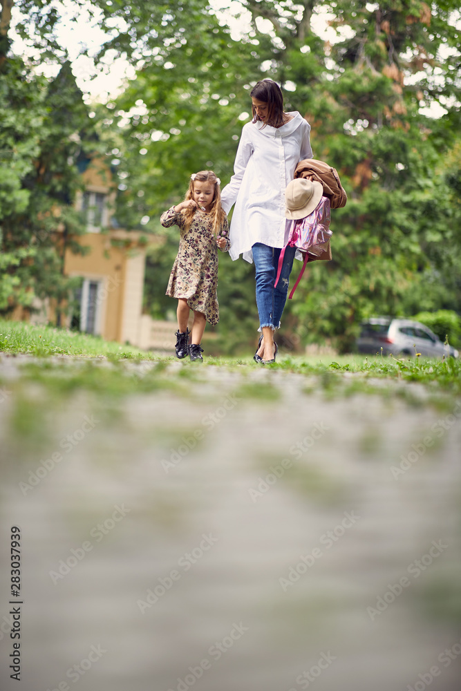 Obraz premium first day at school over, parent and girl going home from school