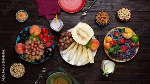 Photos Family table with seasonal fruits, berries, yogurt and nuts, fresh ingredients for lunch