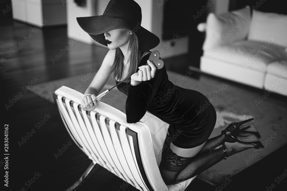 Sexy dominant femme fatale with whip kneeling on sofa black and white  Photos | Adobe Stock