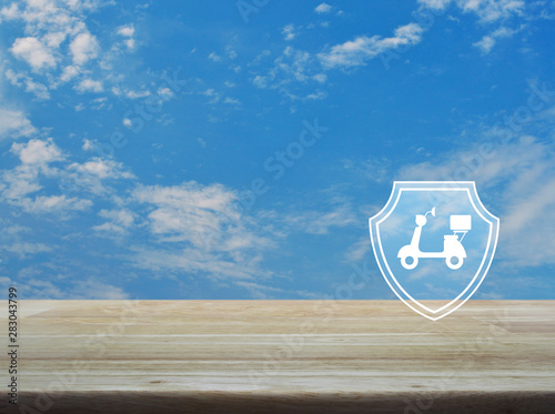 Motorcycle with shield flat icon on wooden table over blue sky with white clouds, Business motorbike insurance concept