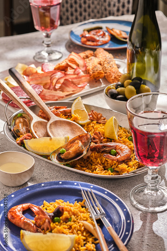 Traditional spanish dinner. Valencian paella. Laid table with wine and rice with seafood