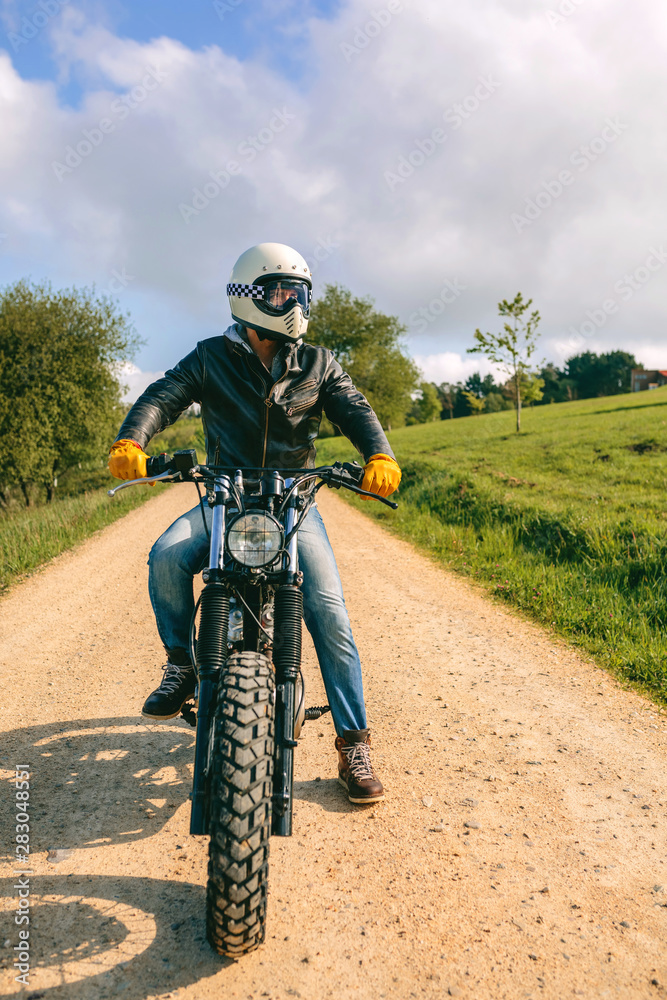 Young man with helmet riding a custom motorbike outdoors Young man with helmet riding a custom motorbike outdoors