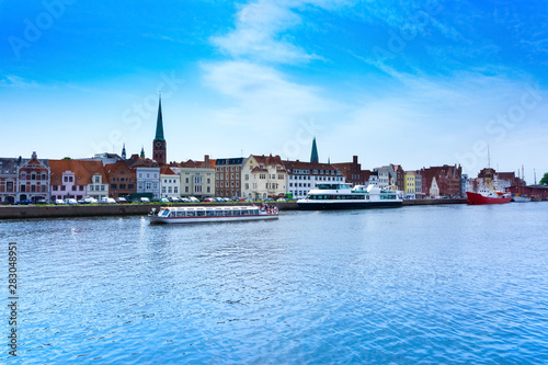 Excursion boat in the Luebecker harbor with a view of the churches and Obertrave river and city view © mstein