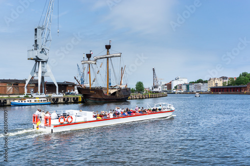 Excursion boat in the Lübecker harbor with a view of a old hanse cog and Obertrave river and city view photo