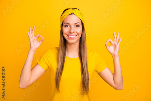 Portrait of lovely millennial showing double okay sign with beaming amile isolated over yellow background photo