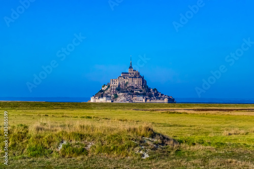 Wallpaper Mural Stunningly beautiful medieval castle of Mont Saint Michel. Abbey, located on the island, enclosed by fortifications. It is washed by the sea from all sides. Beautiful blue sky and fluffy white clouds Torontodigital.ca