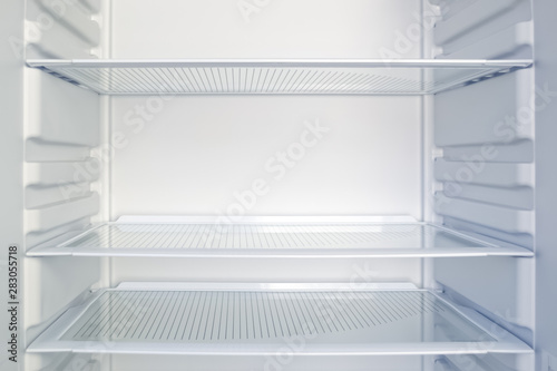 Empty open modern fridge with clean glass shelves. Weight loss, diet and hunger concept