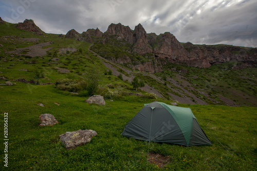 Touristic tent on grass field mountains valley