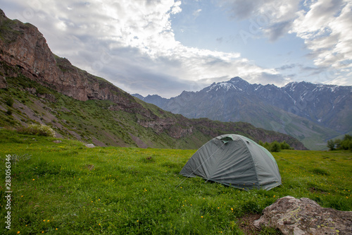 Touristic tent on grass field mountains valley