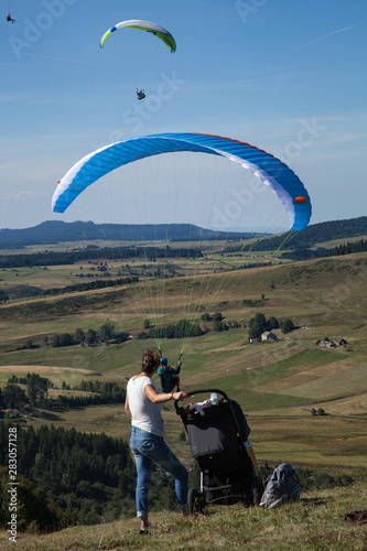 Une femme et son bébé dans un landau regardent l'envol d'un parapentiste photo