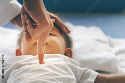 The doctor is using two fingers to press down in the middle of the baby's chest, which is CPR in the case that the child stops breating, to health care and insurance concept. photo