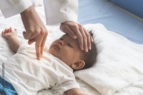 The doctor is using two fingers to press down in the middle of the baby's chest, which is CPR in the case that the child stops breating, to health care and insurance concept.
