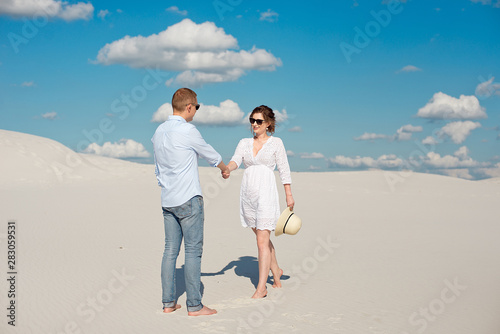 Young couple enjoying the sunset in the dunes. Romantic traveler walks in the desert. Adventure travel lifestyle concept. © Viktoria
