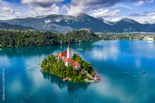 Bled, Slovenia - Aerial view of Lake Bled (Blejsko Jezero) with the Pilgrimage Church of the Assumption of Maria, pletna boats, Bled Castle and Julian Alps on a sunny summer day photo