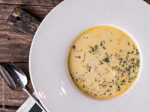 Onion soup in a white plate close-up on wooden table