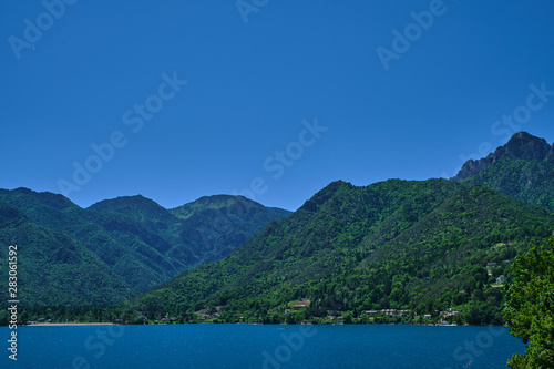Panoramic view of Lake Ledro in the north of Italy In the Alps. Blue lake, in the background green mountains, blue sky. © Berg