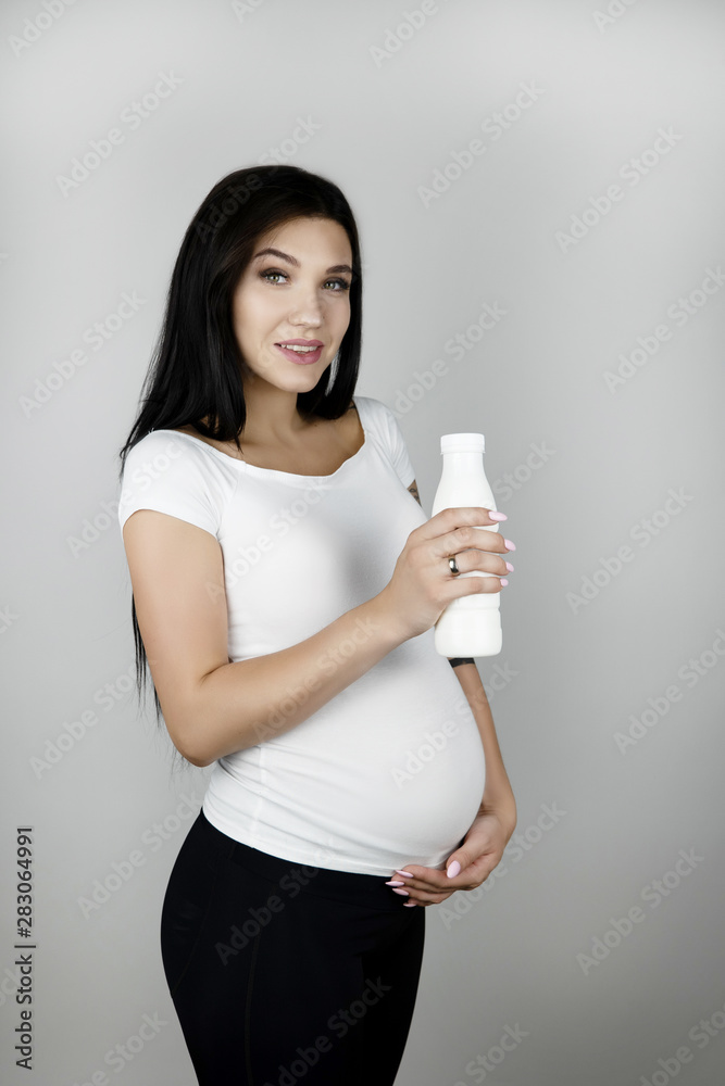beautiful pregnant brunette woman holding bottle with kefir on isolated white background beautiful pregnant brunette woman holding bottle with kefir on isolated white background