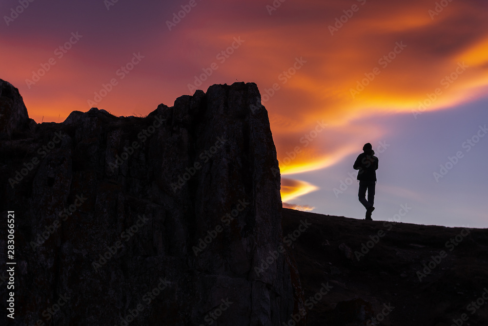 Silhouette photography of person on cliff at twilight, beautiful color shades of sky in the evening