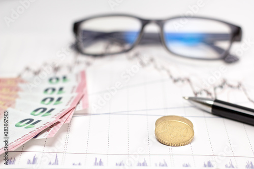 Euro, coin and glasses placed on a graphic chart