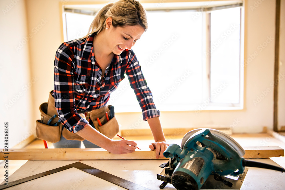 A woman worker in the carpenter workroom renovation - obrazy, fototapety, plakaty 