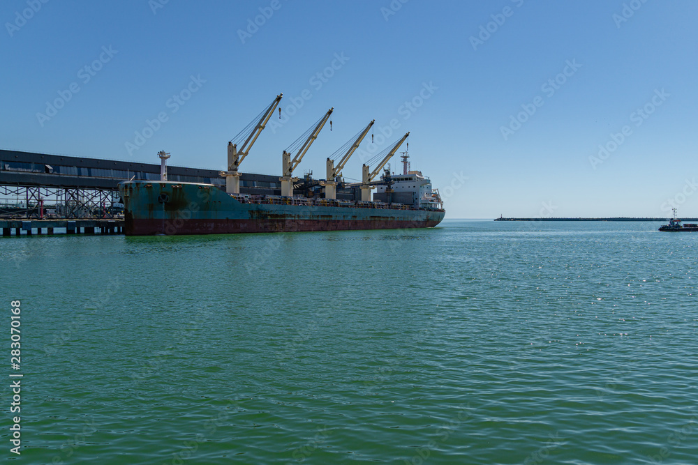 Large blue sea ship dry cargo ship or bulk carrier near bulk terminal in the emerald waters of the Black Sea. Sunny day Large blue sea ship dry cargo ship or bulk carrier near bulk terminal in the emerald waters of the Black Sea. Sunny day