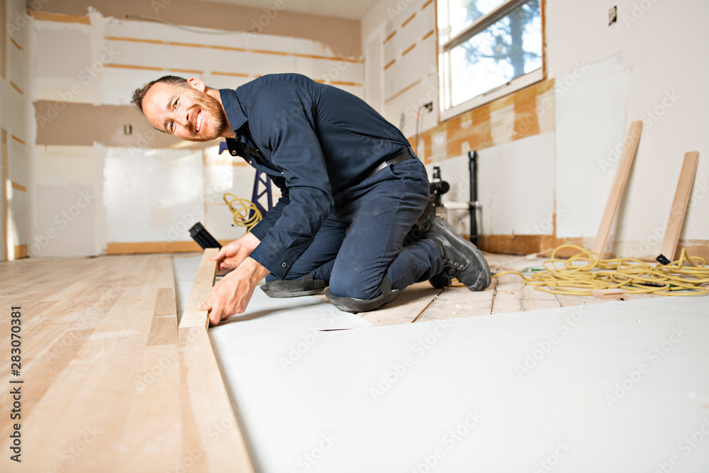 A Male Worker install wood floor on a house