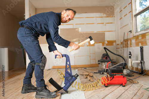 A Male Worker install wood floor on a house