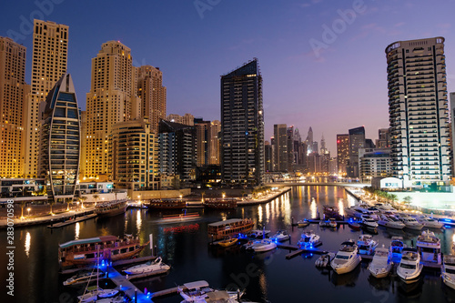 Dubai marina with boats and buildings with gates at night with lights and blue sky, United Arab Emirates © frimufilms