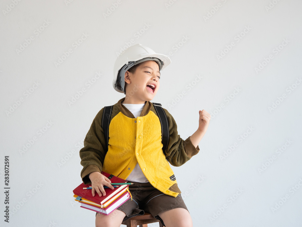 Asian boy with white engineer hat and whiting on the book education concept Asian boy with white engineer hat and whiting on the book education concept