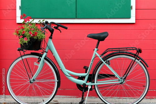 aquamarine bike in front a red wooden house