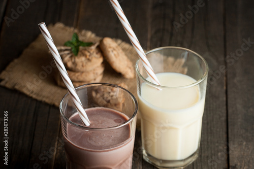 Photo of fresh Made Chocolate Banana Smoothie on a wooden table with cookies, banana and coconut. Milkshake. Protein diet. Healthy food concept.