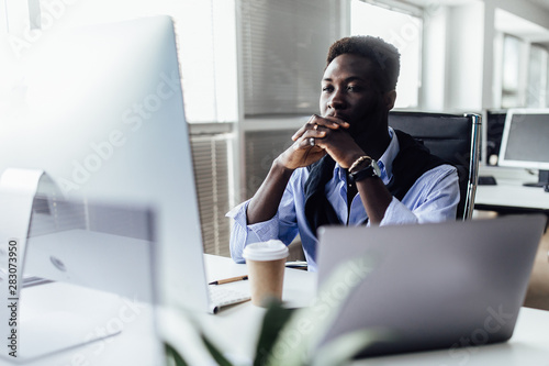 Tensioned or surprised man is sitting in office. Serious and concentrated male in suit is working at notebook and looking resent and worried.