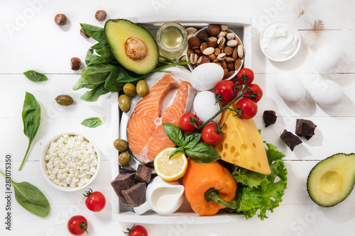 Ketogenic low carbs diet - food selection on white wooden background. Balanced healthy organic ingredients of high content of fats. Nutrition for the heart and blood vessels. Meat, fish and vegetables