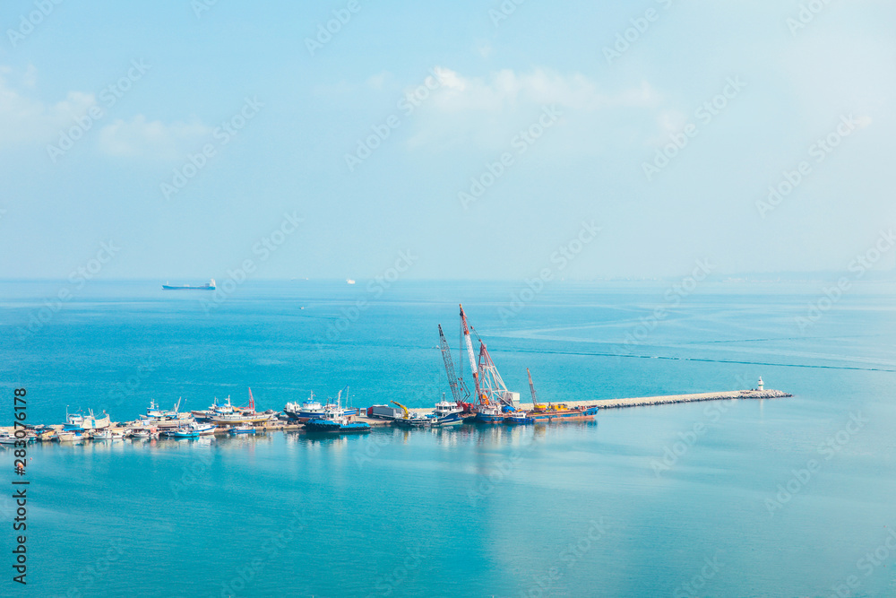 Industrial port or harbor with container or cargo ships and cranes in iskenderun seaport at Hatay city of Turkey. Transportation and logistic at Mediterranean sea. 