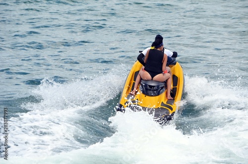 Young couple riding tandem on a yellow jet ski