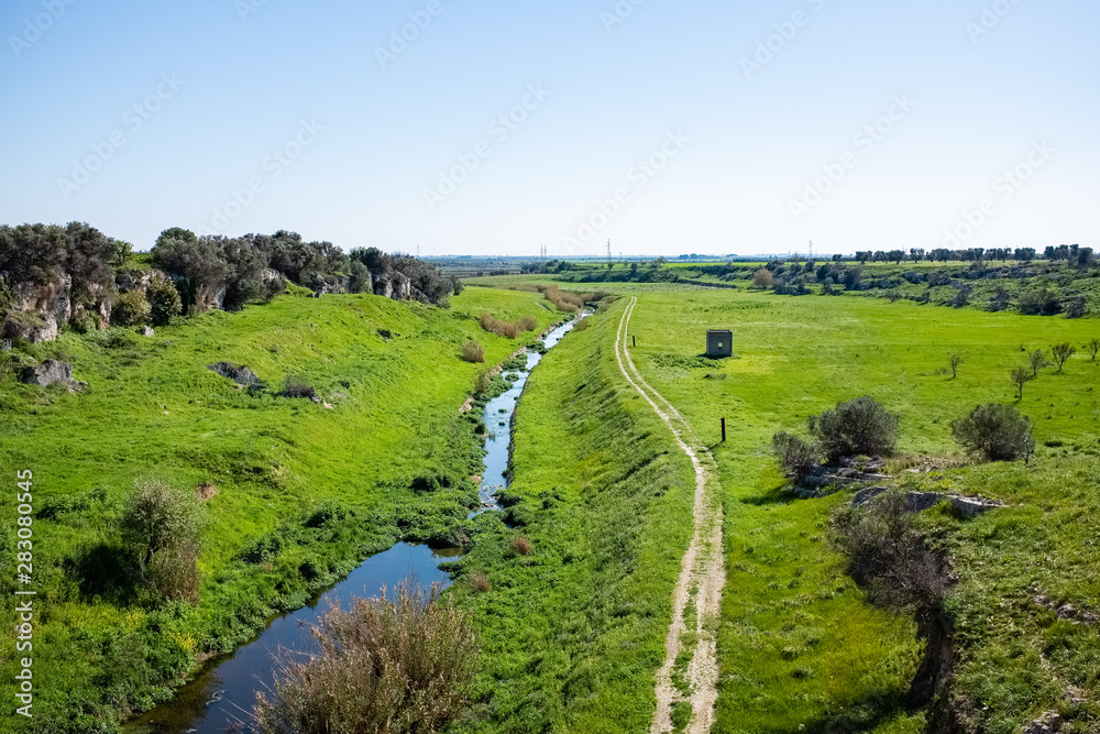 Beautiful view over Apulian countryside with small river and gravel road. Puglia region, Italy