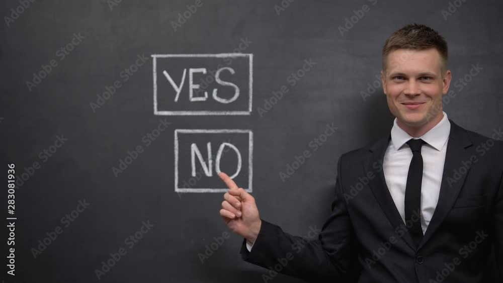 Smiling politician pointing finger into no sign painted on blackboard, choice Smiling politician pointing finger into no sign painted on blackboard, choice