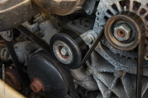 Serpentine drive belt tensioner idler pulley on automobile engine with alternator and water pump pulleys on each side