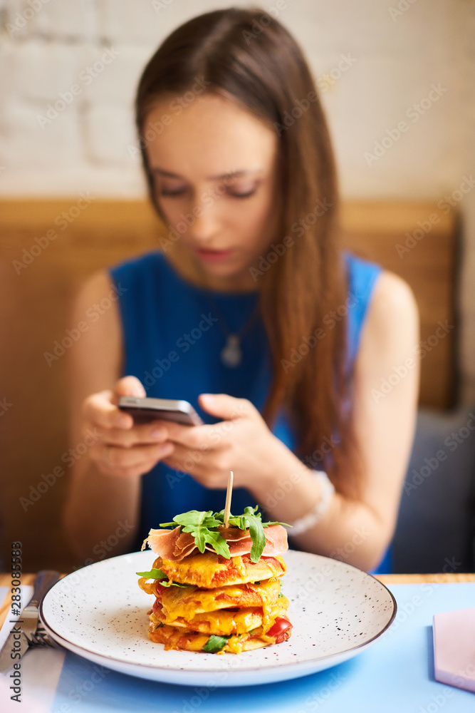 Beautiful young woman with mobile phone eating tasty pancake in cafe Beautiful young woman with mobile phone eating tasty pancake in cafe