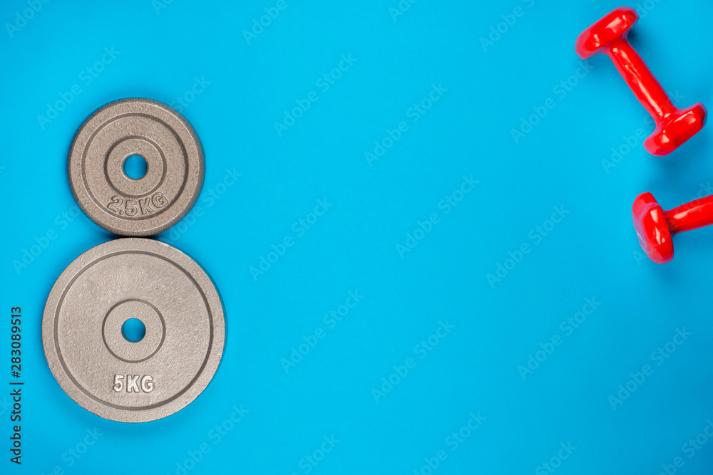 A pair of weights on blue background, shot from above. A pair of weights on blue background, shot from above.