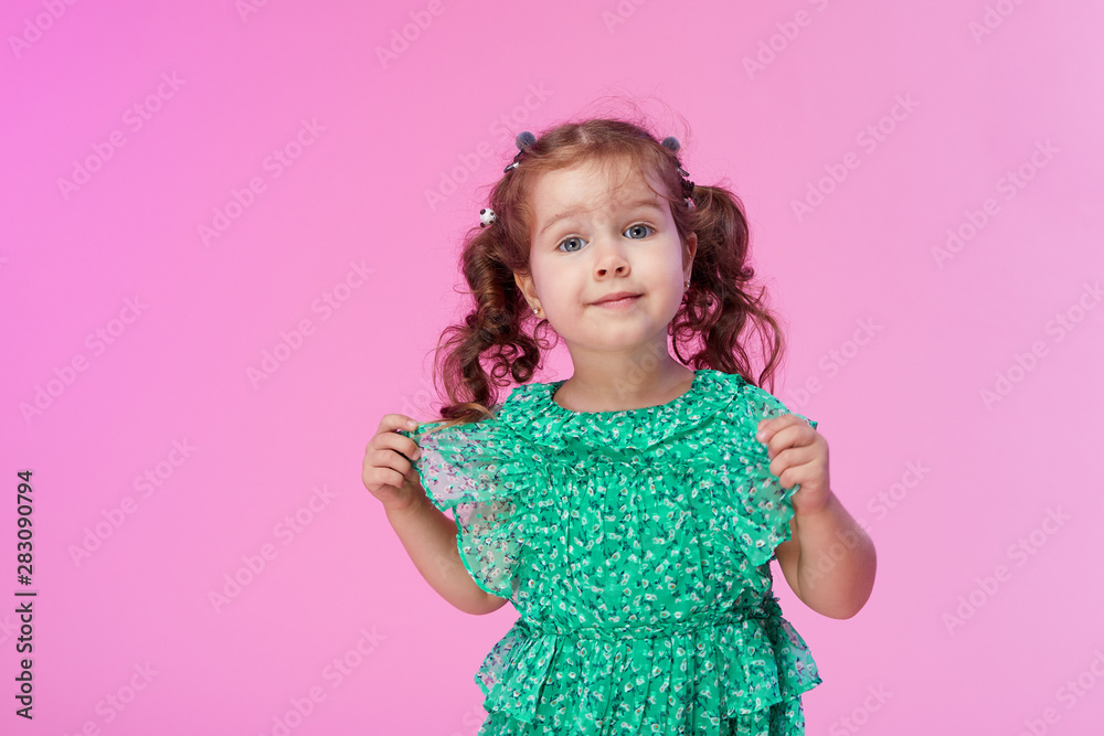 Funny little kid, toddler girl in fashionable green dress isolated on pink background Funny little kid, toddler girl in fashionable green dress isolated on pink background