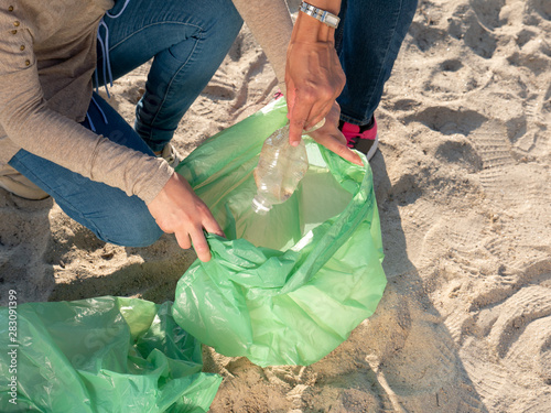 two people picking rubbish on the beach