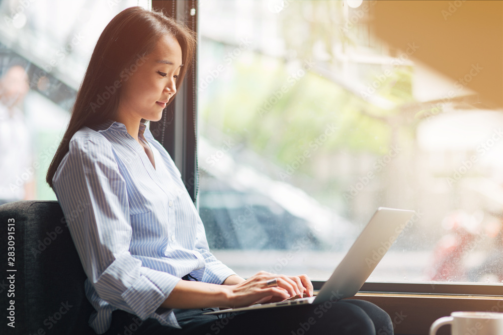 Focused on her work. Concentrated girl working at a coffee shop. Concept of female freelancer business. Copy space on the right side Focused on her work. Concentrated girl working at a coffee shop. Concept of female freelancer business. Copy space on the right side