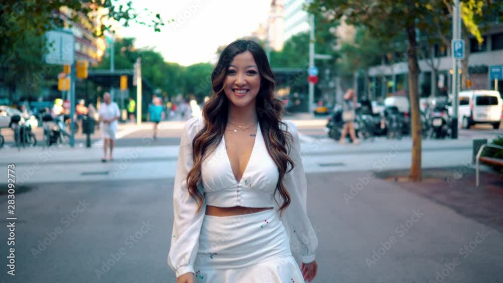 Summer sunny lifestyle portrait of young stylish asian girl on the street of big modern city. She wears white dress. women business Summer sunny lifestyle portrait of young stylish asian girl on the street of big modern city. She wears white dress. women business