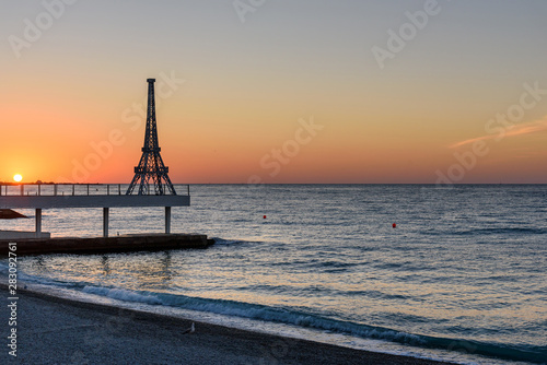 A small copy of the Eiffel Tower on the beach of Yalta, in the north of the setting sun and a clear, cloudless sky.