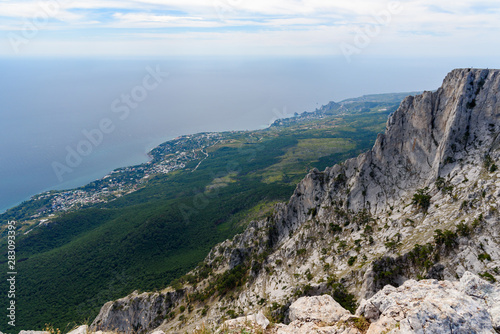 view of the resort city of Yalta from the top of Mount Ai-Petri  on a bright sunny day with clouds in the sky.