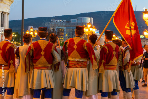 International parade in the streets of Skopje, Macedonia with traditional costume folk dress. Ready to dance in the festival. Big flag of Montenegro with montenegrin people