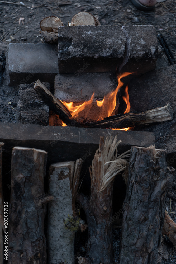 Burning fire in a campfire for cooking on a fire on a summer evening. Travel and tourism as a lifestyle. Vertical Burning fire in a campfire for cooking on a fire on a summer evening. Travel and tourism as a lifestyle. Vertical
