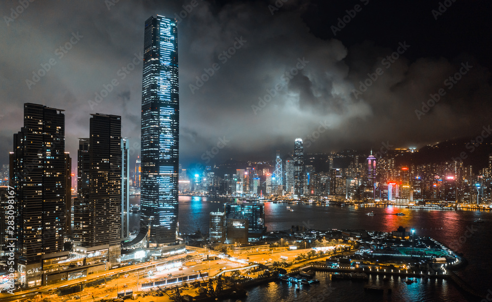 Hong Kong cityscape at night, skyscrapers and tall buildings at Victoria Harbour, drone aerial view. Asia travel destination, Asian tourism, modern city life, or business finance and economy concept
