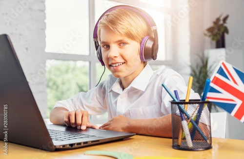 Smiling boy at the laptop enjoys learning English online